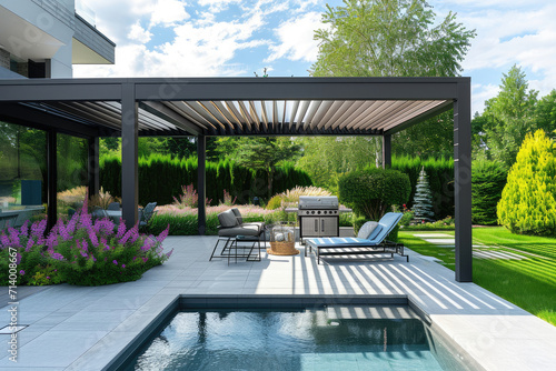 Trendy outdoor patio pergola shade structure, awning and patio roof, pool, garden lounge, chairs, metal grill surrounded by landscaping, with a flowers garden photo