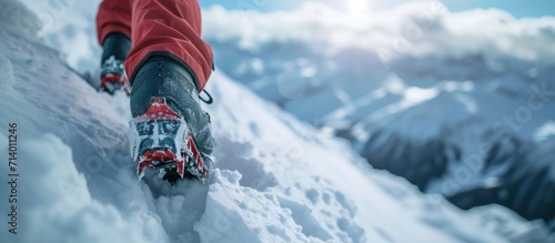 Tourist climbing snowy mountain with boot crampons.