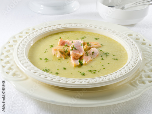Sopa de salmón en plato de porcelana blanco sobre mesa. Hake in green sauce on plate and white background