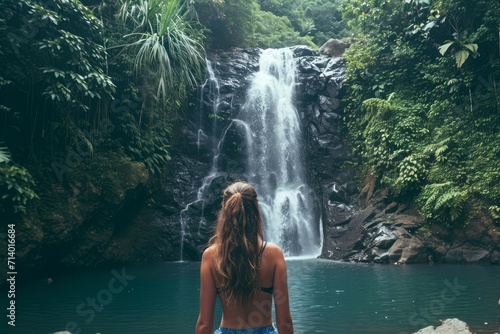 Woman in front of a waterfall in a tropical forest, adventure. Generative AI