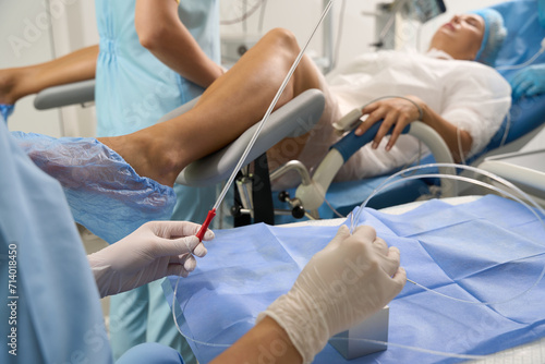 Medical tube in hands of doctor in front of blurred pregnant woman photo