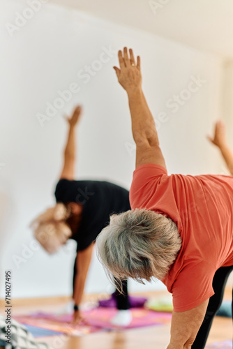 A group of senior women engage in various yoga exercises, including neck, back, and leg stretches, under the guidance of a trainer in a sunlit space, promoting well-being and harmony