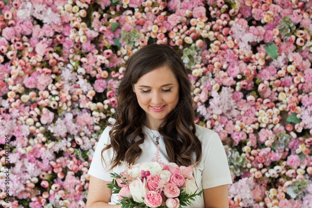 Fototapeta premium Cute lady with flowers. Happy brunette woman indoor portrait