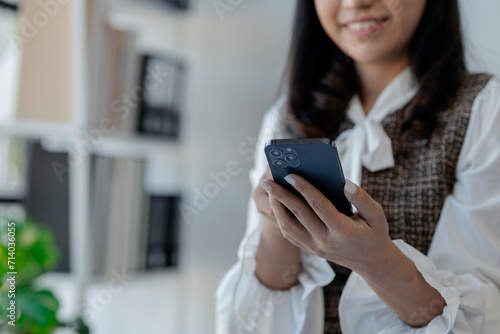 An entrepreneur is talking on the phone with a company customer, Beautiful woman in the office, happy, businesswoman checks email on smartphone, manager uses mobile phone,