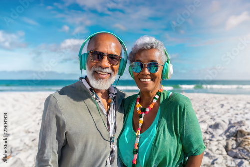  Elderly couple in sunglasses and headphones, smiling and enjoying a beach moment © Marko