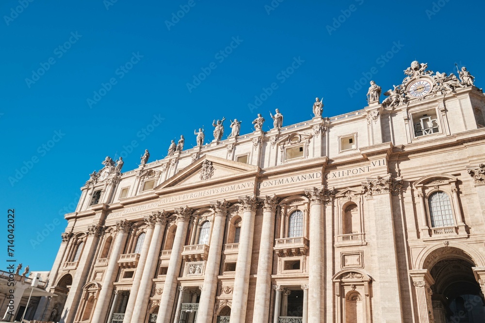 View of Saint Peter's Basilica and it's facade detail with Corinthian order columns and  blue sky, Rome, Italy