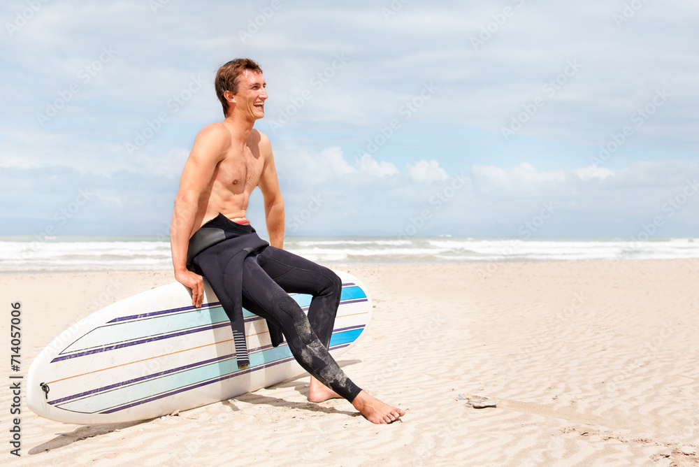 Thinking, beach and shirtless man with surfboard on space in wetsuit for sports, travel or fitness. Nature, vision and body of young surfer laughing with sand by ocean for exercise on blue sky Thinking, beach and shirtless man with surfboard on space in wetsuit for sports, travel or fitness. Nature, vision and body of young surfer laughing with sand by ocean for exercise on blue sky