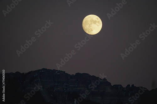 Golden moonrise over mountains at dusk