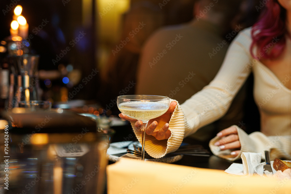A girl takes a glass of sparkling champagne at a bar.