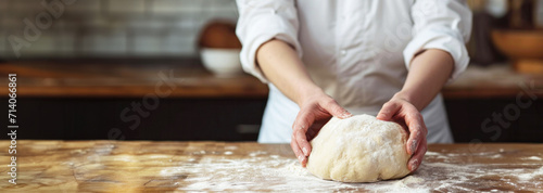 Chef kneading dough on wooden countertop with flour, bakery, hands at work, food preparation, artisan bread, a baking concept with visible texture. Banner with copy space.