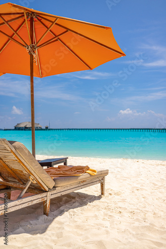 Outdoor tourism landscape. Luxury beach resort closeup beach chairs or beds under umbrellas with palm trees  sea sand blue sky. Summer leisure travel vacation background. Colorful sunny coast relax 