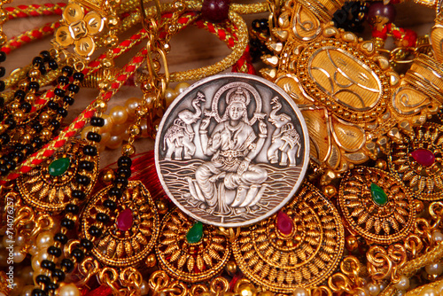 gold jewelery IN wooden Durga, Saraswati or laxmi silver coin isolated on white background . indiaan god.