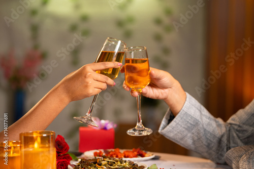 Close up shot of couples hands toasting wine glasses during candlelight dinner at restaurant - concept of romantic date night party for special occasion