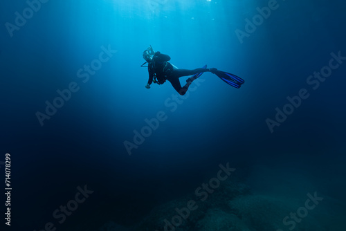 Scuba Diver Swimming in Deep Sea With Sunrays. Young Man DIver Eploring Sea Life.