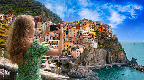 .A tourist girl taking a picture of Manarola, Liguria, Italy