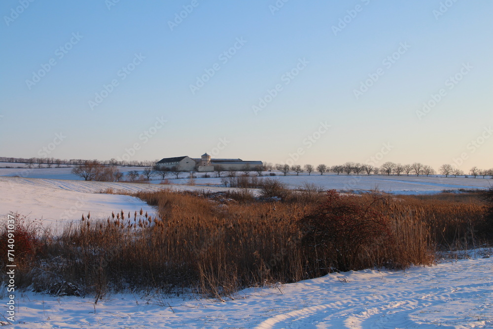 A snowy field with a house in the distance