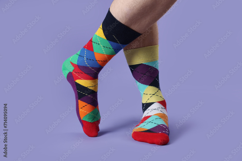 Man in different colorful socks on violet background, closeup