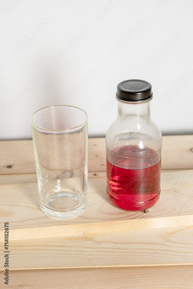 Glass bottle filled with refreshing liquid sits on the table in a bar, surrounded by glass Glass bottle filled with refreshing liquid sits on the table in a bar, surrounded by glass