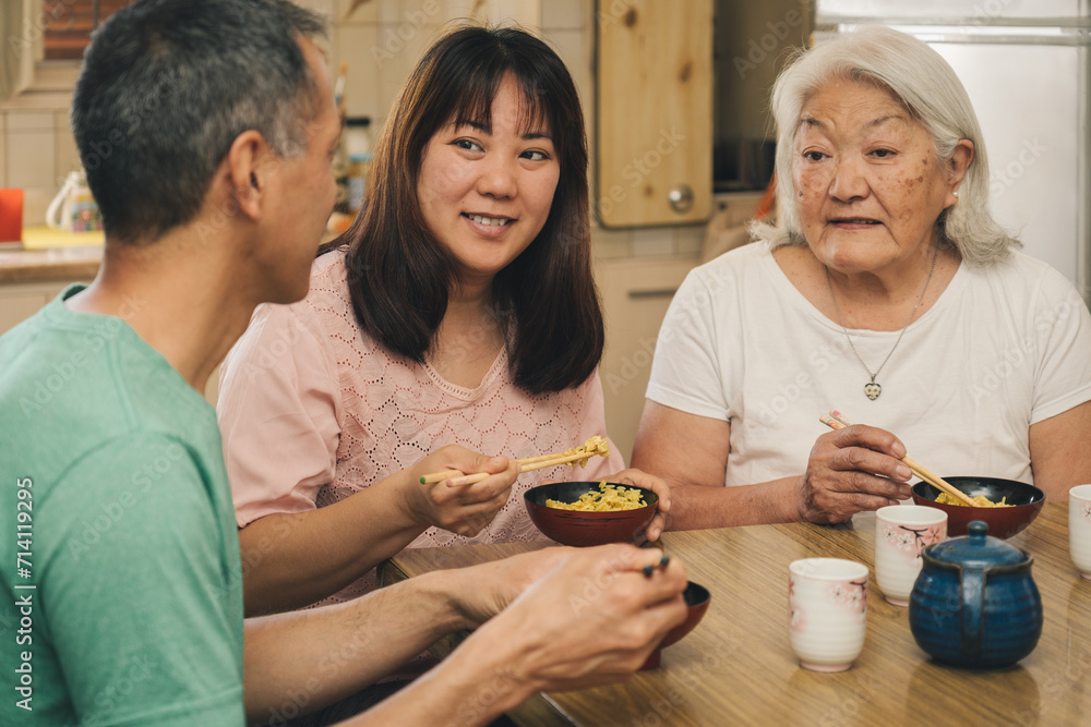 Older mother with her adult children eating rice with chopsticks. Older mother with her adult children eating rice with chopsticks.