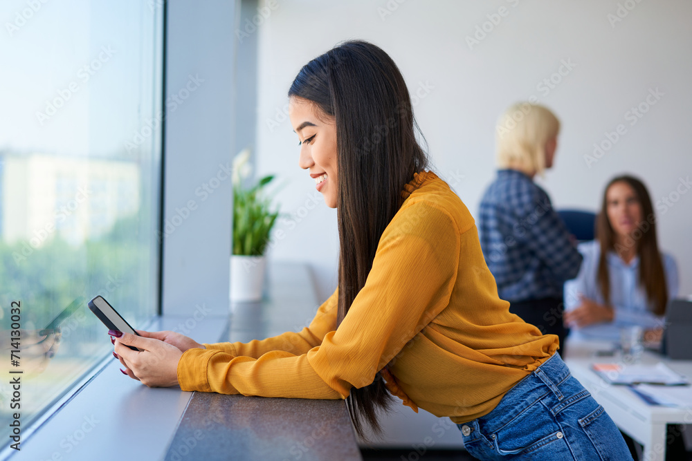 Fototapeta premium Young woman using her phone at office