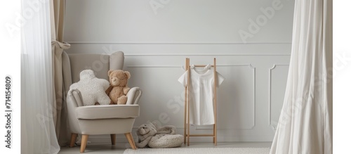 Contemporary, simple kid's room with a cozy gray chair, stuffed animal, and white t-shirt on wooden stand. © 2rogan