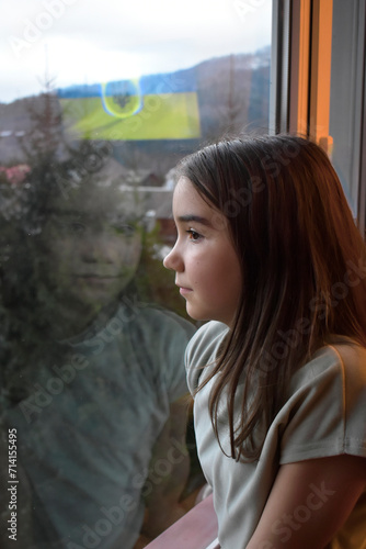 child looking out window, country flag, independence and freedom, war in Ukraine