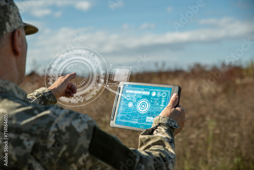 AI technology in the army. Warfare analytic operator checking coordination of the military team. Military commander with a digital tablet device with artificial intelligence operating troops outdoors