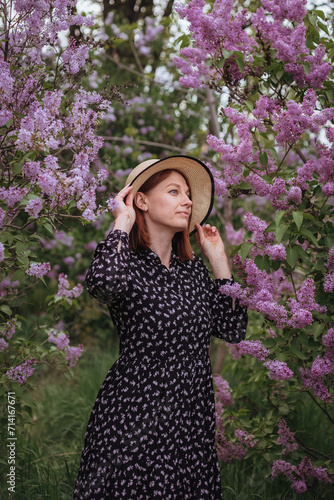 Woman in a hat in the park. A garden where lilacs bloom.