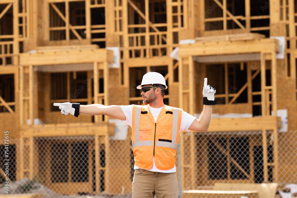 roofer builder working on roog structure of building on construction site. handsome young male builder in hard hat smiling at camera. Construction Worker on Duty. Contractor and the Wooden House Frame roofer builder working on roog structure of building on construction site. handsome young male builder in hard hat smiling at camera. Construction Worker on Duty. Contractor and the Wooden House Frame