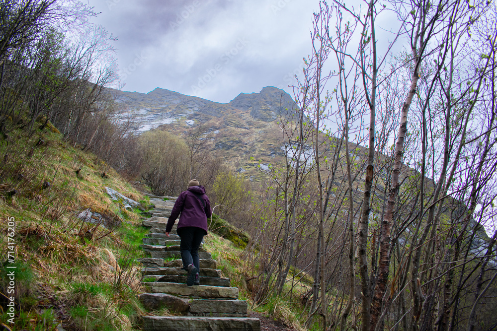 Female hiker climbing Old stone staircase once used by ancient monks. Reine, Lofoten, Norway