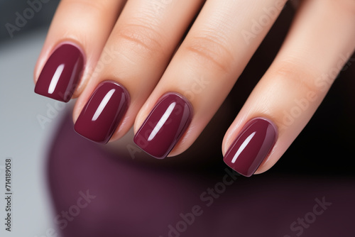 Woman hand with burgundy color nail polish on her fingernails. Burgundy nail manicure with gel polish at luxury beauty salon. Nail art and design. Female hand model. French manicure.