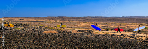 Surfers walking in the desert in search for waves