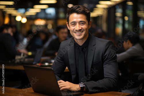 A confident, successful Asian businessman with a laptop, exuding positivity and professionalism in an office.