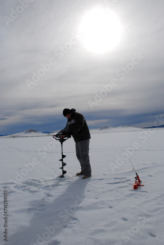 Ice fisherman drilling a hole