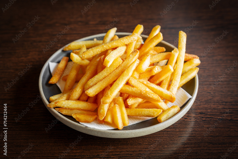 French fries in a plate on a dark wooden background French fries in a plate on a dark wooden background