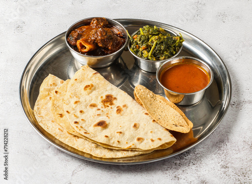 Mutton korma thali set with mixed vegetable of aloo palak, shorba, nachos and chapati served in dish isolated on background top view of indian spicy food