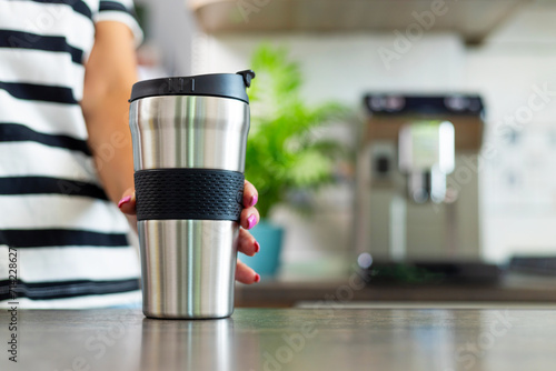Hand Holding Stainless Steel Travel Mug in Kitchen photo