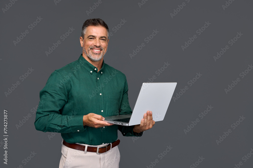 Happy middle aged business man ceo wearing green shirt standing isolated on gray using laptop. Smiling mature businessman professional executive manager looking at camera holding computer. Portrait Happy middle aged business man ceo wearing green shirt standing isolated on gray using laptop. Smiling mature businessman professional executive manager looking at camera holding computer. Portrait