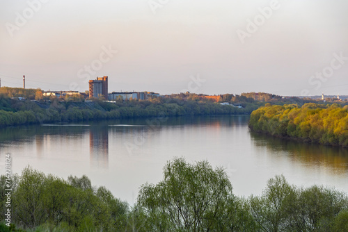 Wide river in autumn evening, view from the height of the hill..Autumn landscape view of a wide river from an observation deck..View of factory chimneys near a wide river, autumn landscape. © Sergei