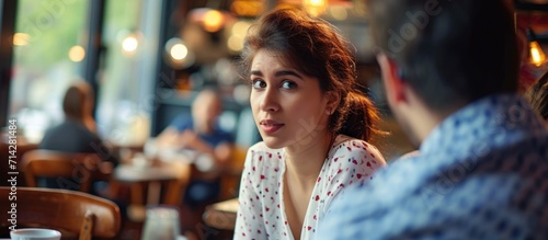 Doubtful Hispanic woman eavesdropping on man in coffee shop. photo