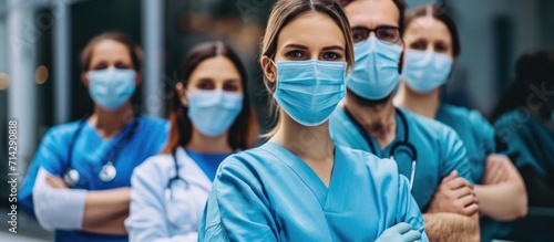 Healthcare workers in face masks, standing with crossed arms, looking at camera.
