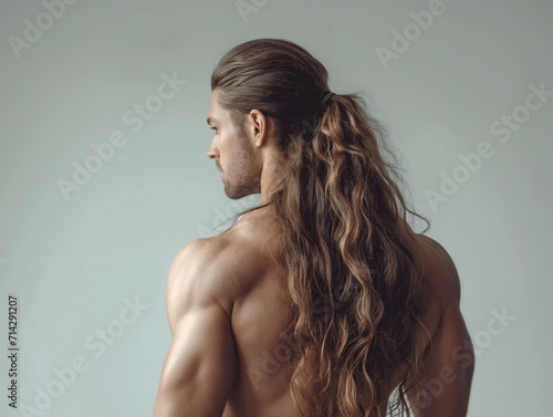 Athletic back and muscular shoulders of a young man with long hair on a gray background. Health and sport concept. Advertising banner for a fitness studio.