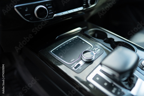 Focus on round pushbutton control of multi media interface with touchpad on center console of luxury car. Tactile sensor being activated by fingers photo