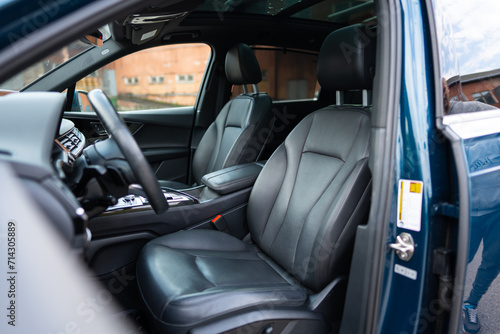Side view of front seats inside brand new auto from driver's side with open door. High-quality interior material of car cabin reflecting character of vehicle photo