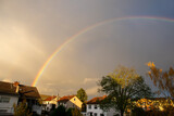 Panoramic view of rainbow with dark clouds over houses after a rainstorm