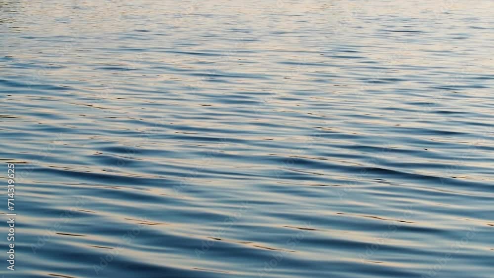 Blurry background of water - water surface, small ripples on the water, evening light Blurry background of water - water surface, small ripples on the water, evening light