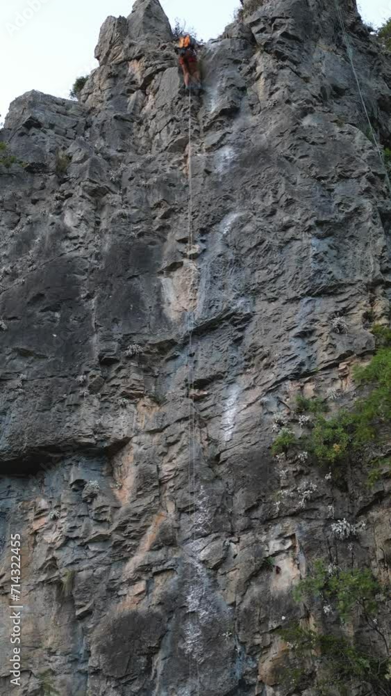 Timelapse of a male climber who climbs to the climbing rock. He wears a red safety helmet and yellow backpack. Timelapse of a male climber who climbs to the climbing rock. He wears a red safety helmet and yellow backpack.