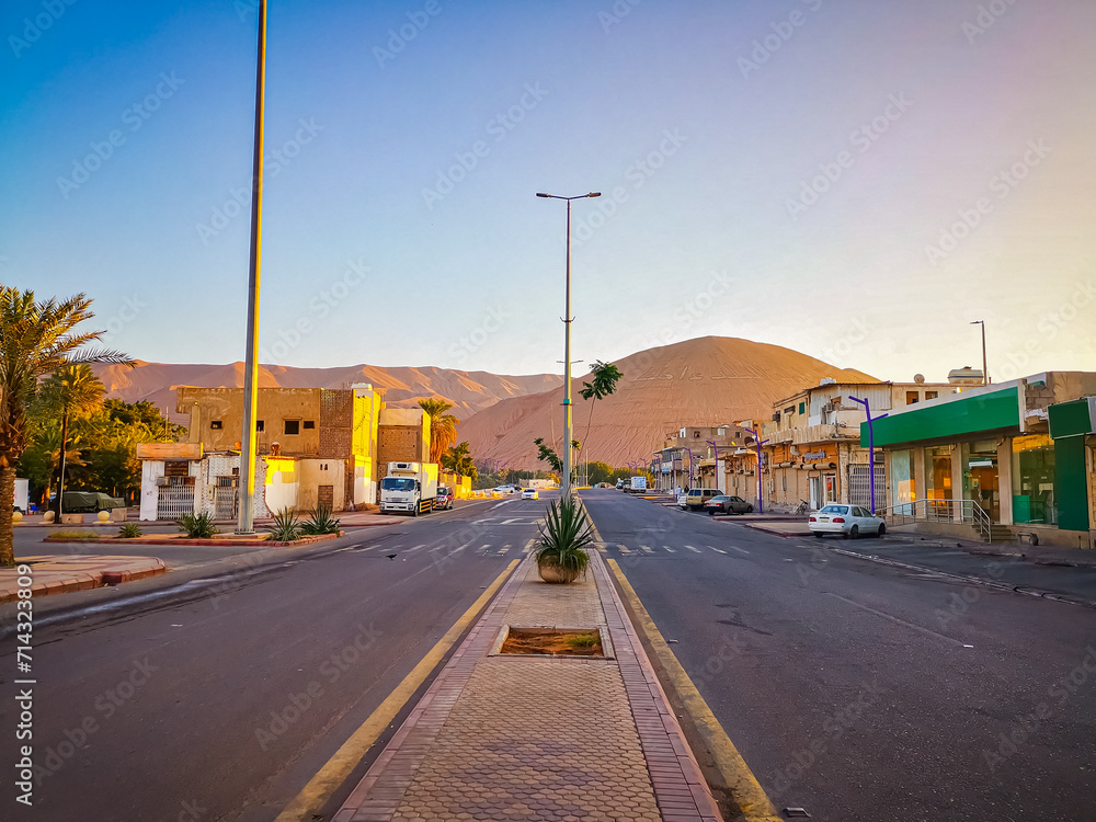City with sand dunes behind. Beautiful city in the desert with blue sky. Urban area in Saudi Arabia built on mountain. 