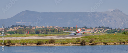 Prepare to landing, Orange red white airplane from behind just before touching down on Corfu airport runway, Greece