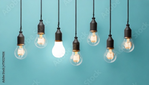 hanging light bulbs with glowing one different idea on light blue background minimal concept idea flat lay top
